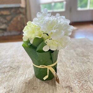 Potted white and light yellow hydrangea in a raffia wrapped pot.